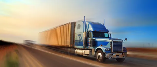Blue tractor-trailer in motion on an open highway